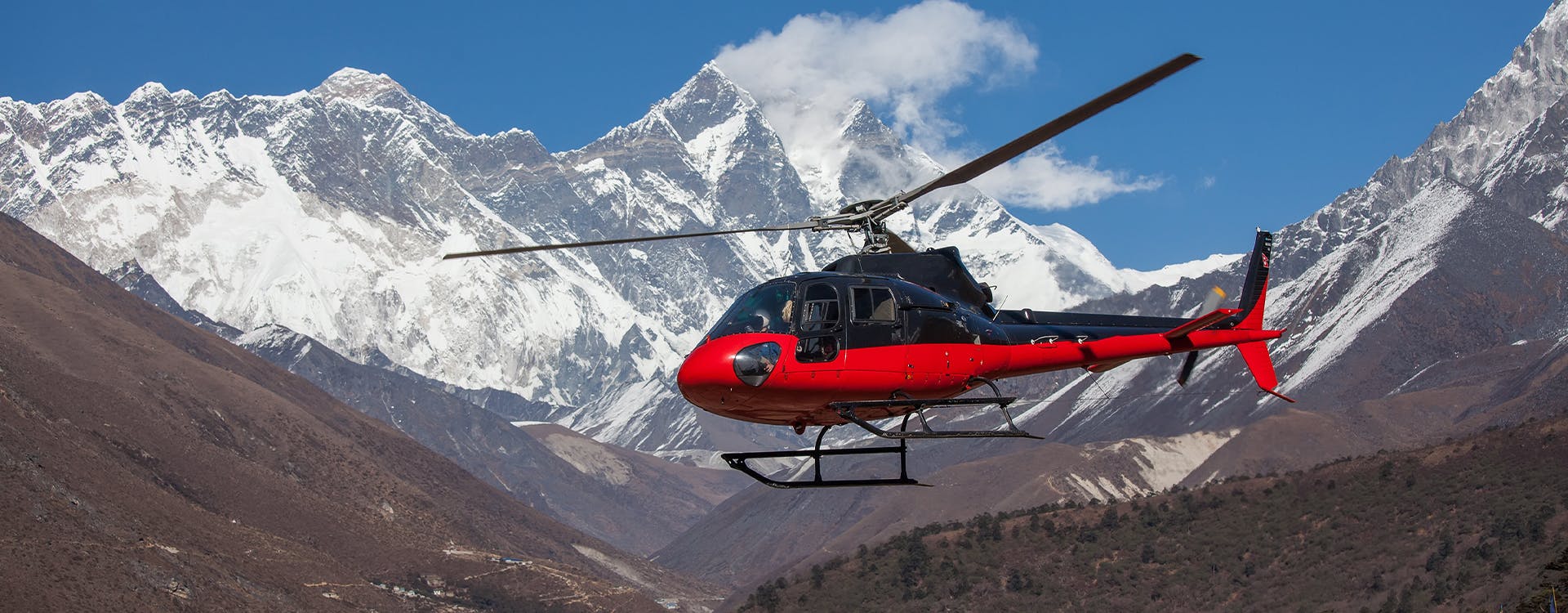 heli flying infront of snow capped mountain