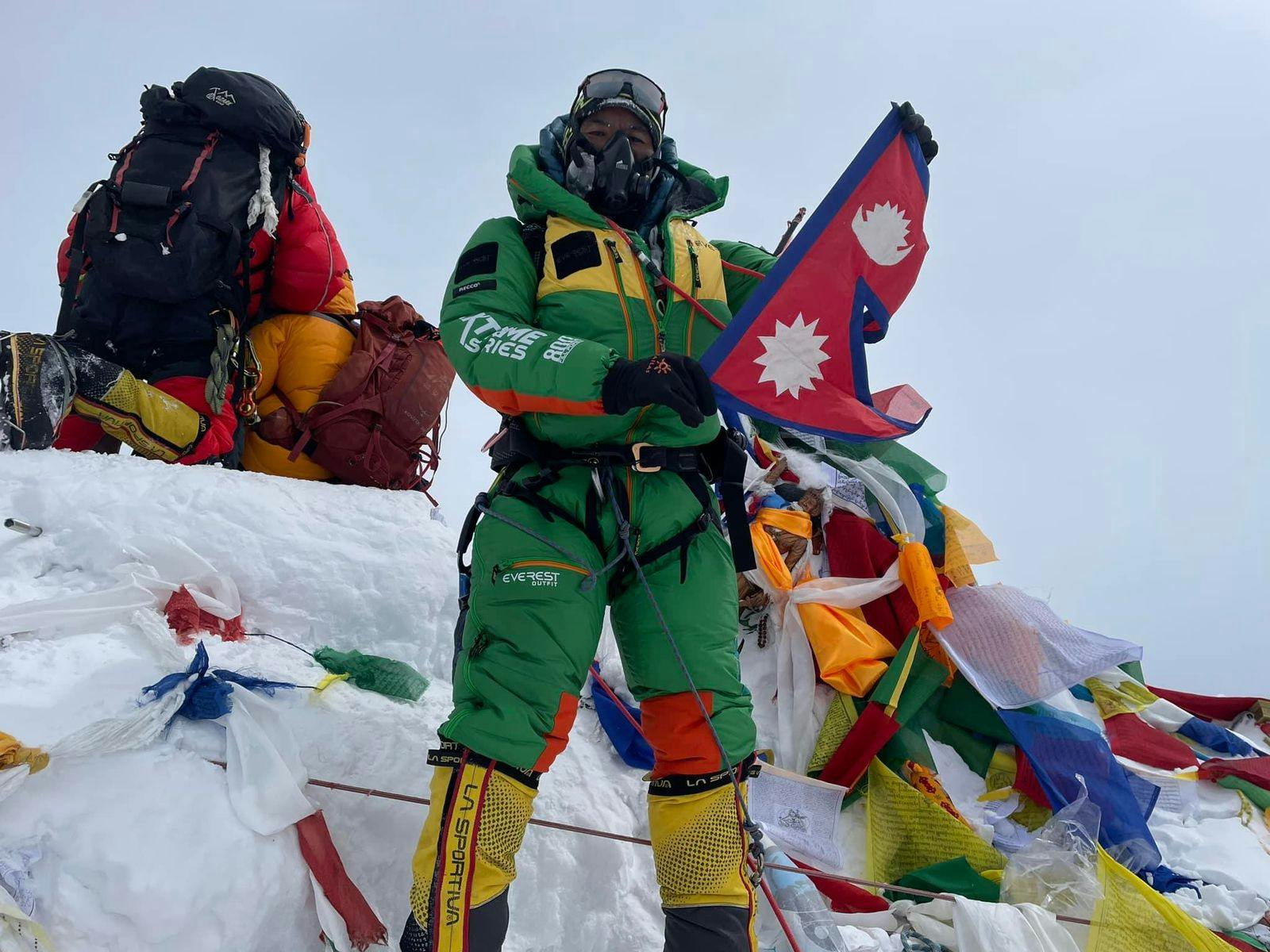 climber displaying nepal flag at mount everest