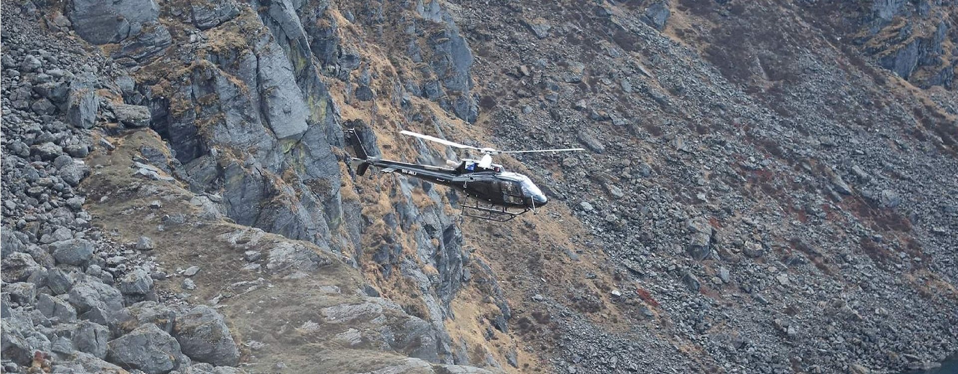 Helicopter taking off between the mountains